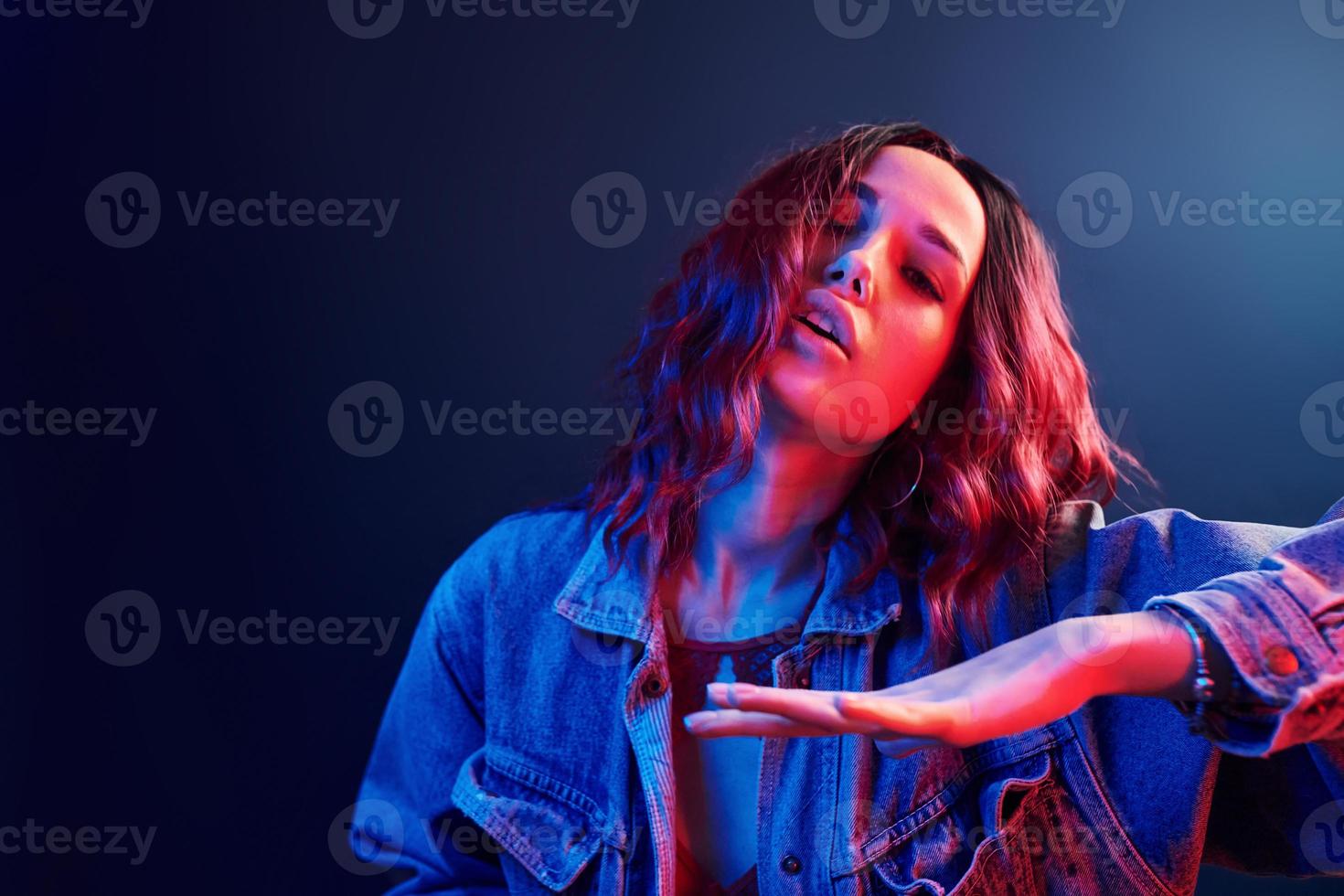 portrait de jeune fille aux cheveux bouclés qui danse en néon rouge et bleu en studio photo