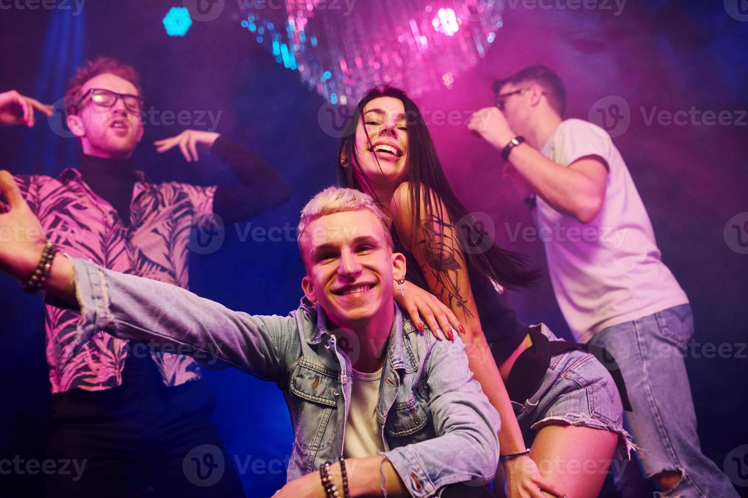 devenir fou et poser pour la caméra ensemble. les jeunes s'amusent dans une boîte de nuit avec des lumières laser colorées photo