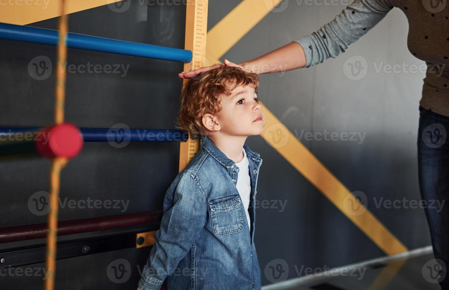 enseignant mesurant la taille de l'enfant à l'intérieur à la maternelle photo