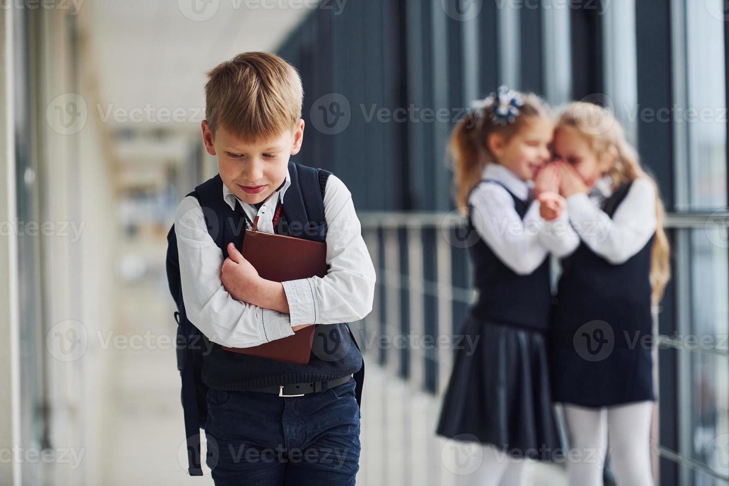 petit garçon est victime d'intimidation. conception du harcèlement. écoliers en uniforme ensemble dans le couloir photo