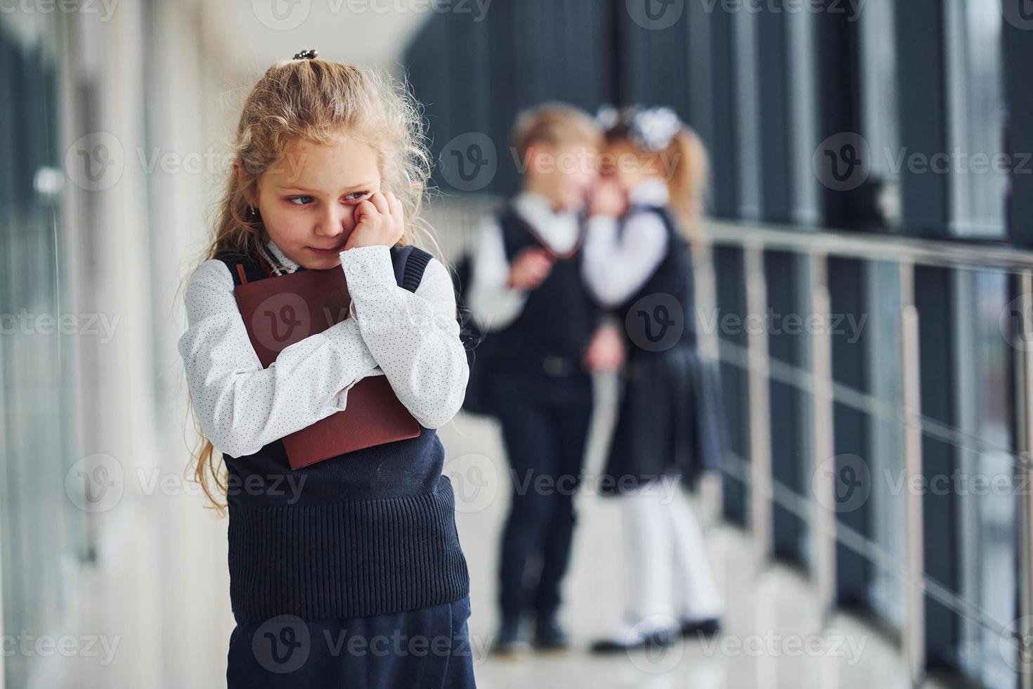 petite fille se fait intimider. conception du harcèlement. écoliers en uniforme ensemble dans le couloir photo