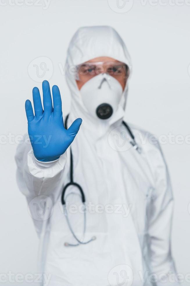 montre le geste d'arrêt à la main. homme médecin scientifique en blouse de laboratoire, lunettes défensives et masque photo