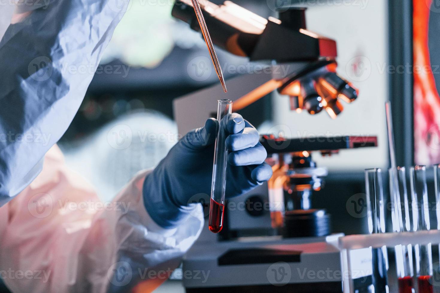 scientifique en uniforme de protection blanc près des écrans avec des données fonctionne avec des coronavirus et des tubes sanguins en laboratoire photo