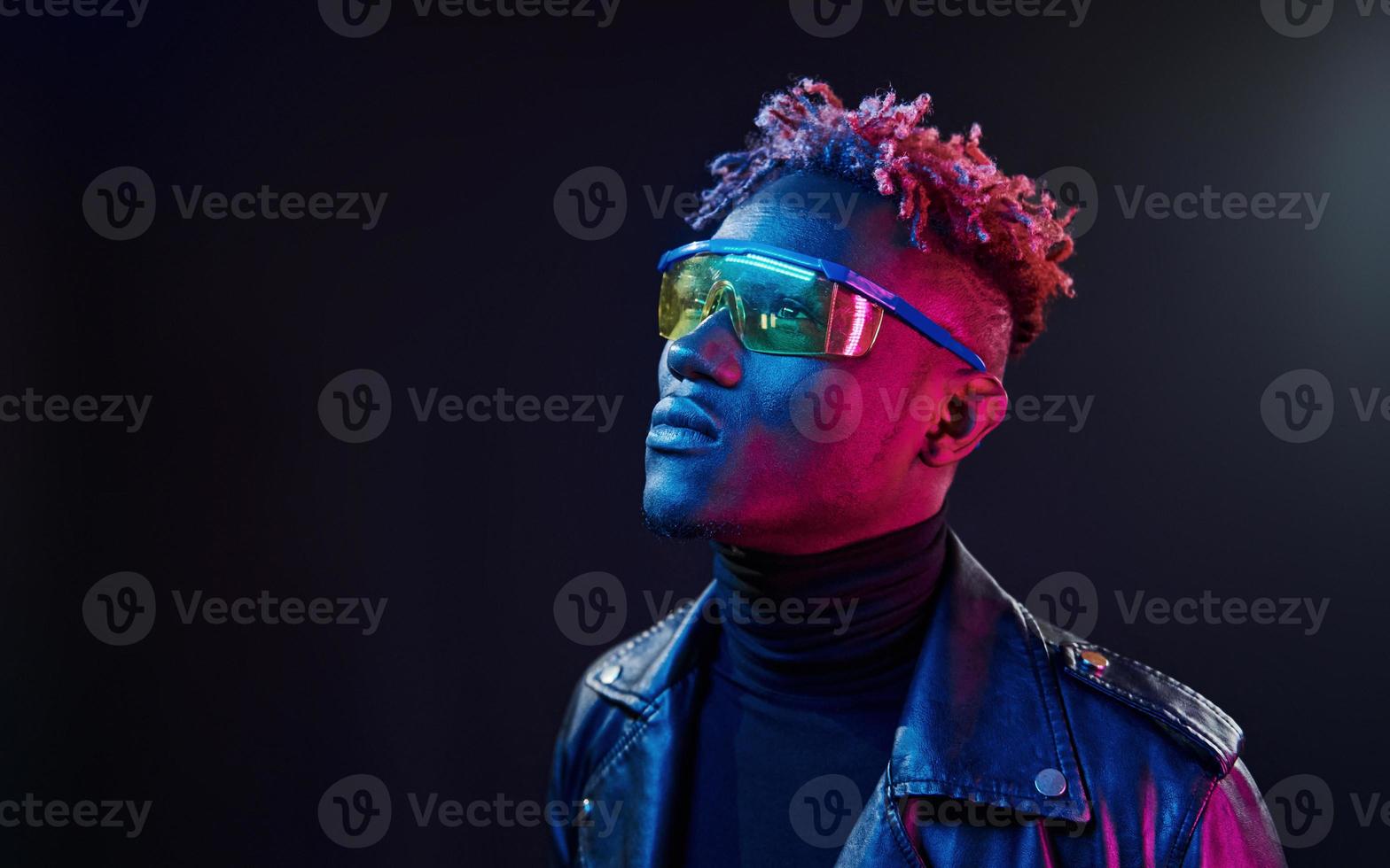 dans des verres. éclairage néon futuriste. jeune homme afro-américain dans le studio photo