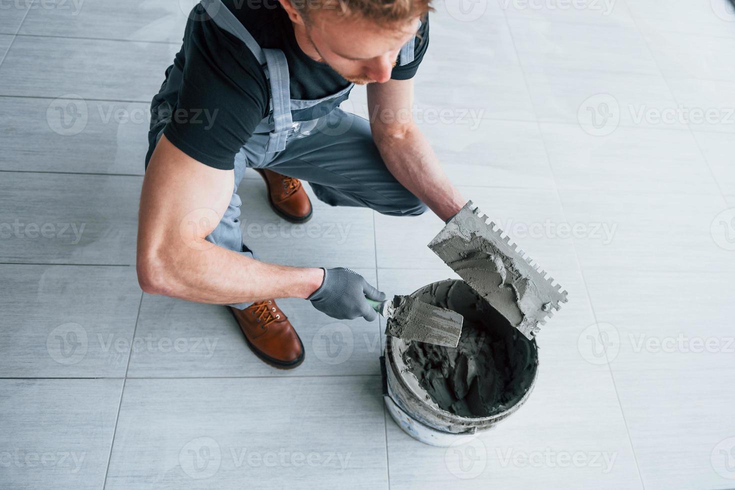 un homme en uniforme gris travaille avec une assiette à l'intérieur dans un grand bureau moderne pendant la journée photo