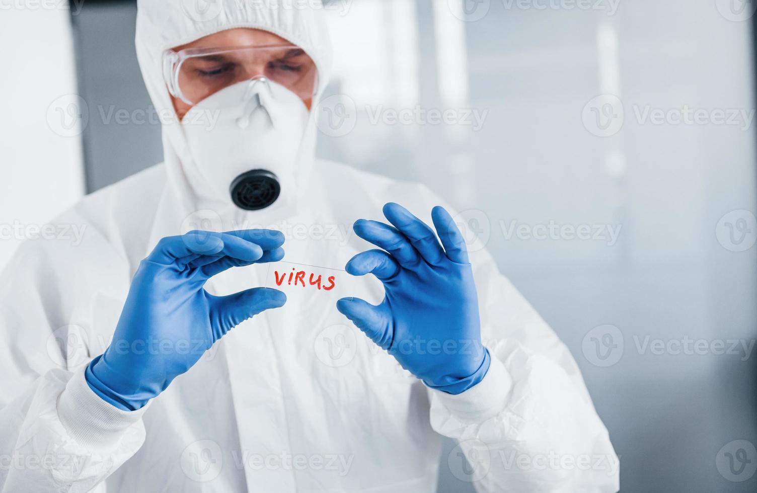 médecin scientifique de sexe masculin en blouse de laboratoire, lunettes défensives et masque contient du verre avec le mot virus dessus photo
