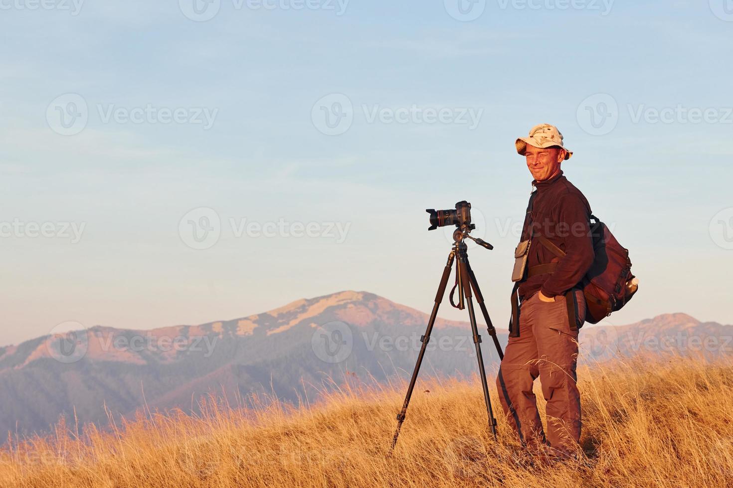 photographe masculin debout et travaillant dans un paysage majestueux d'arbres d'automne et de montagnes à l'horizon photo