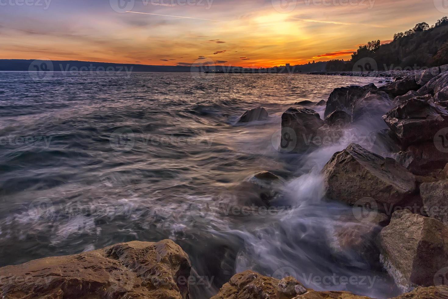 coucher de soleil sur la mer avec des éclaboussures sur les rochers photo