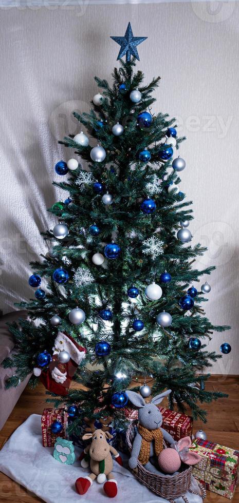 arbre de noël avec des boules colorées et des coffrets cadeaux sur un mur de briques blanches avec des boules bleues et blanches photo