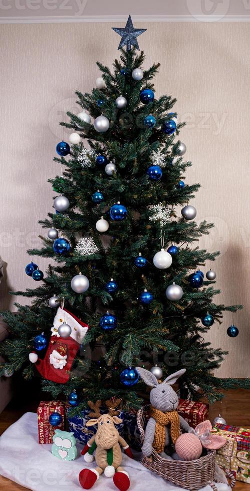 arbre de noël avec des boules colorées et des coffrets cadeaux sur un mur de briques blanches avec des boules bleues et blanches photo