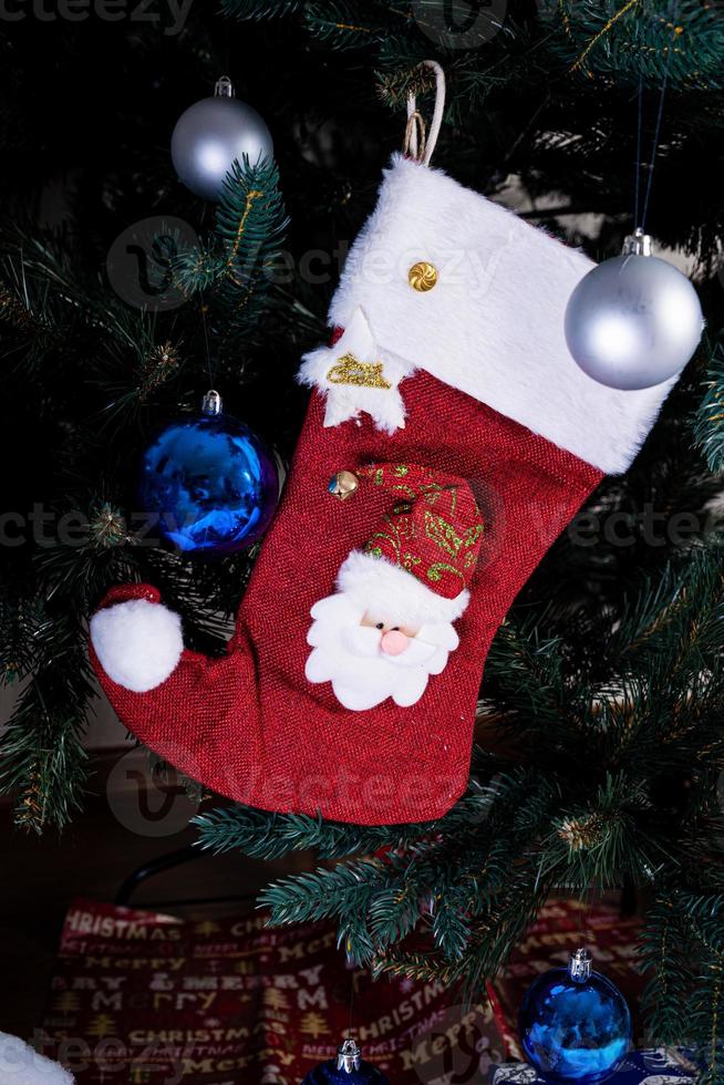 bas de noël. chaussette rouge avec des flocons de neige pour les cadeaux du père noël accrochés au sapin de noël. vacances d'hiver photo
