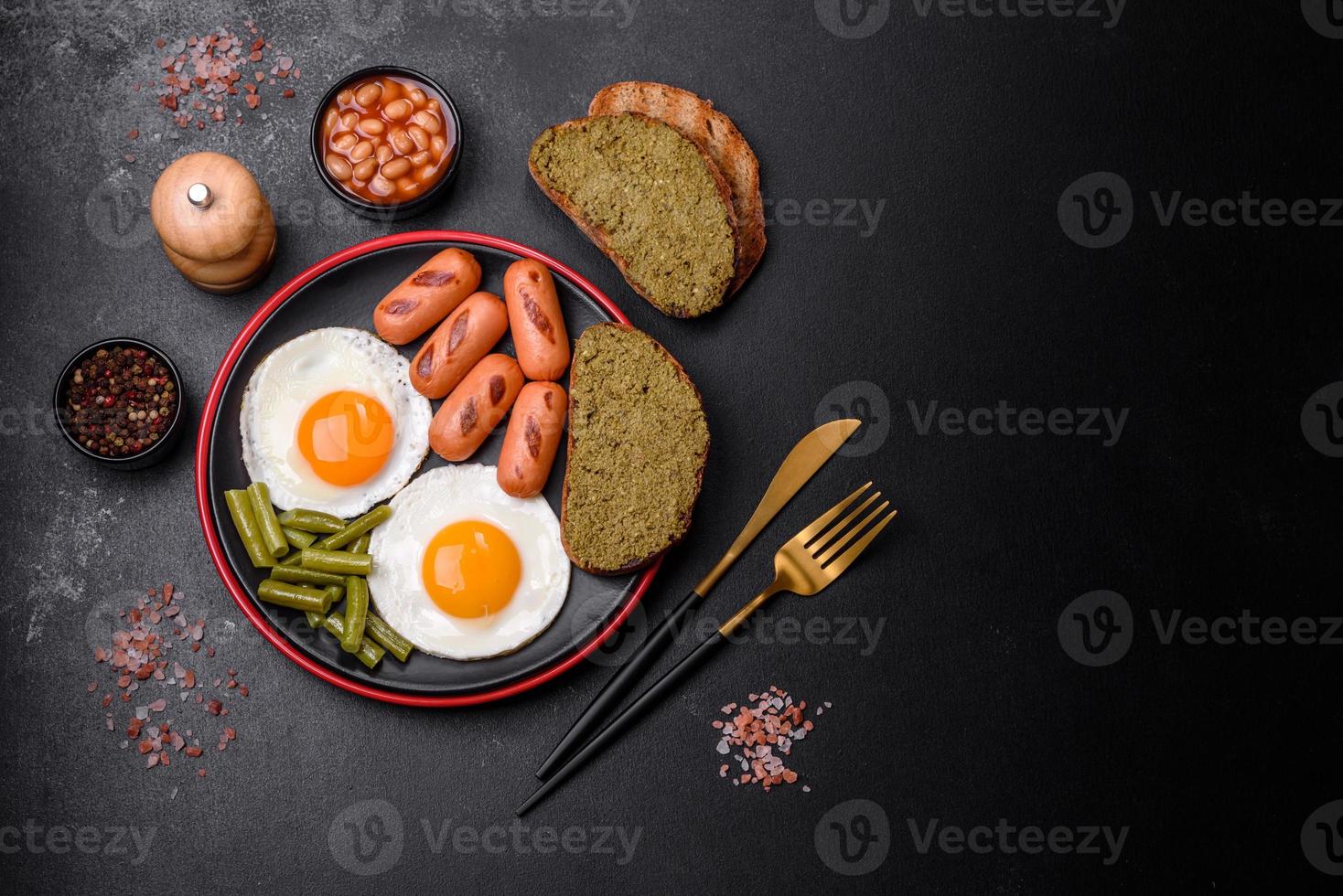 savoureux petit-déjeuner anglais composé d'œufs au plat, de haricots, d'asperges, de saucisses aux épices et d'herbes photo