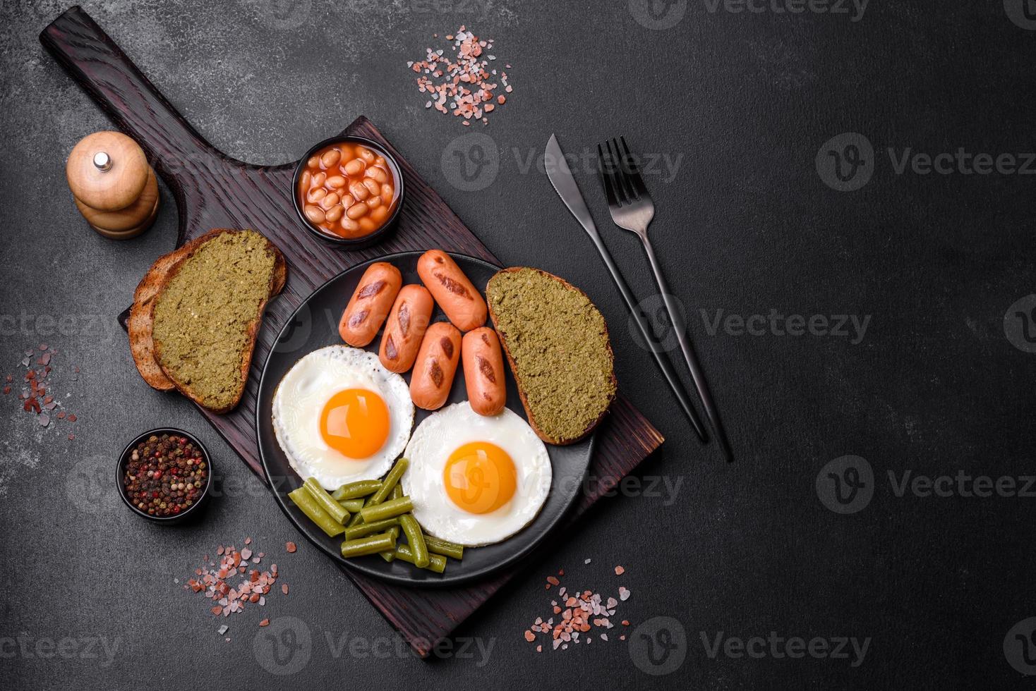 savoureux petit-déjeuner anglais composé d'œufs au plat, de haricots, d'asperges, de saucisses aux épices et d'herbes photo