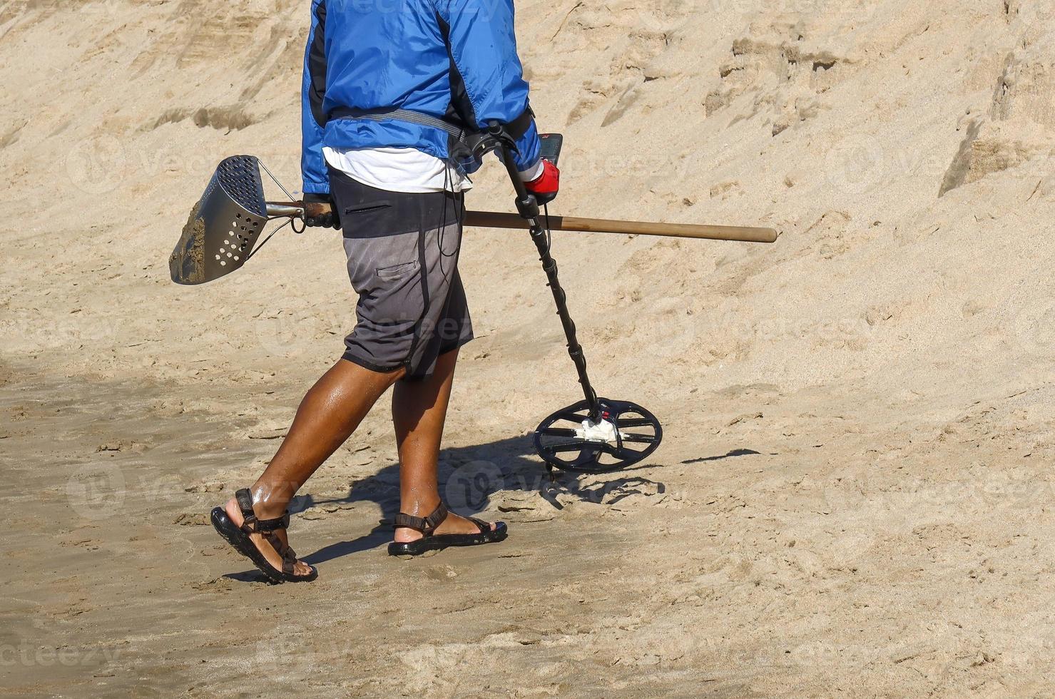 homme avec un détecteur de métaux sur une plage de sable photo