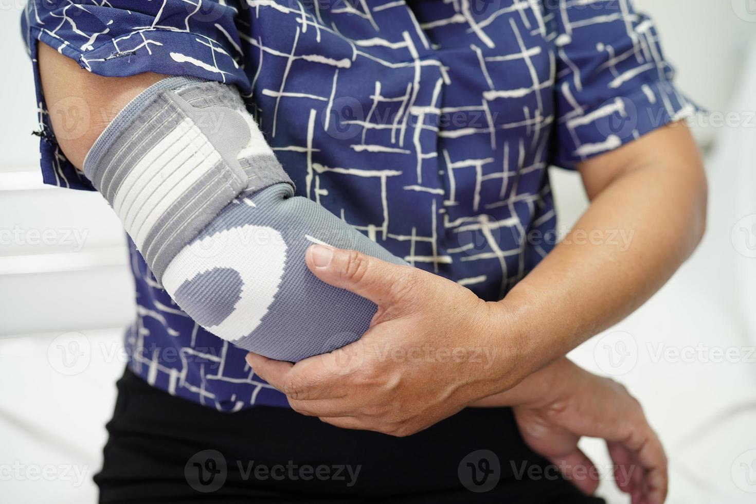 femme senior asiatique portant une attelle de coude à support élastique pour réduire la douleur. photo