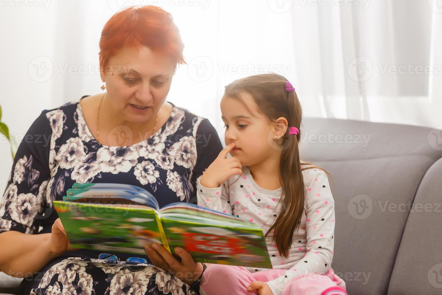 portrait d'une femme âgée et d'une petite fille allongée sur un lit en lisant un livre photo