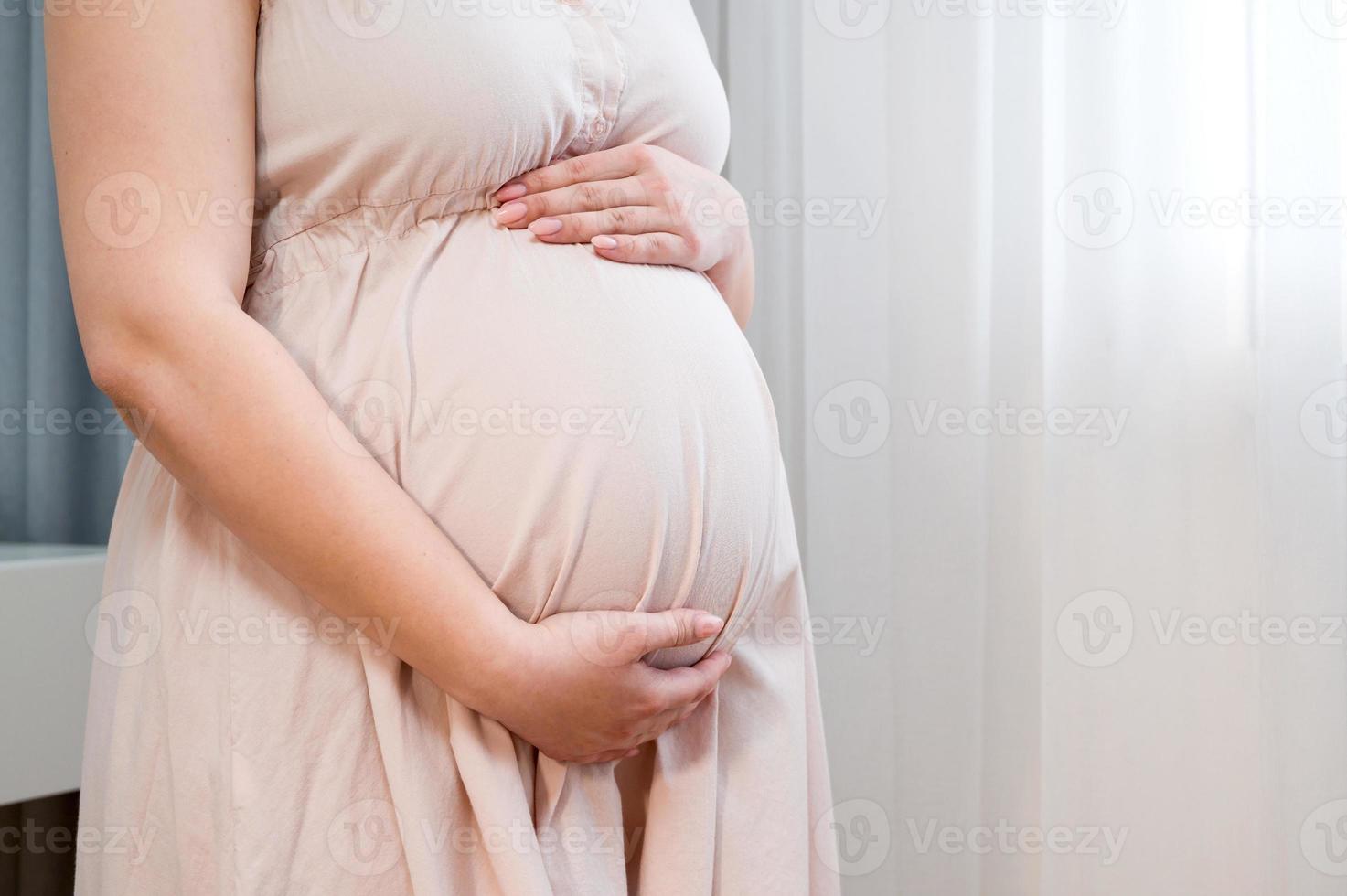 femme enceinte tenant le ventre debout près de la fenêtre. concept de maternité et de grossesse bannière copyspace photo