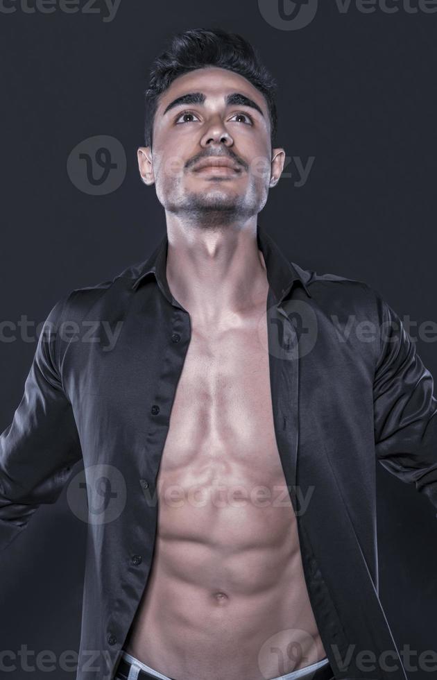 beau modèle masculin arabe avec un corps parfait qui pose en studio. portrait d'un modèle masculin athlétique posant sur fond sombre dans le studio. notion de mode. photo