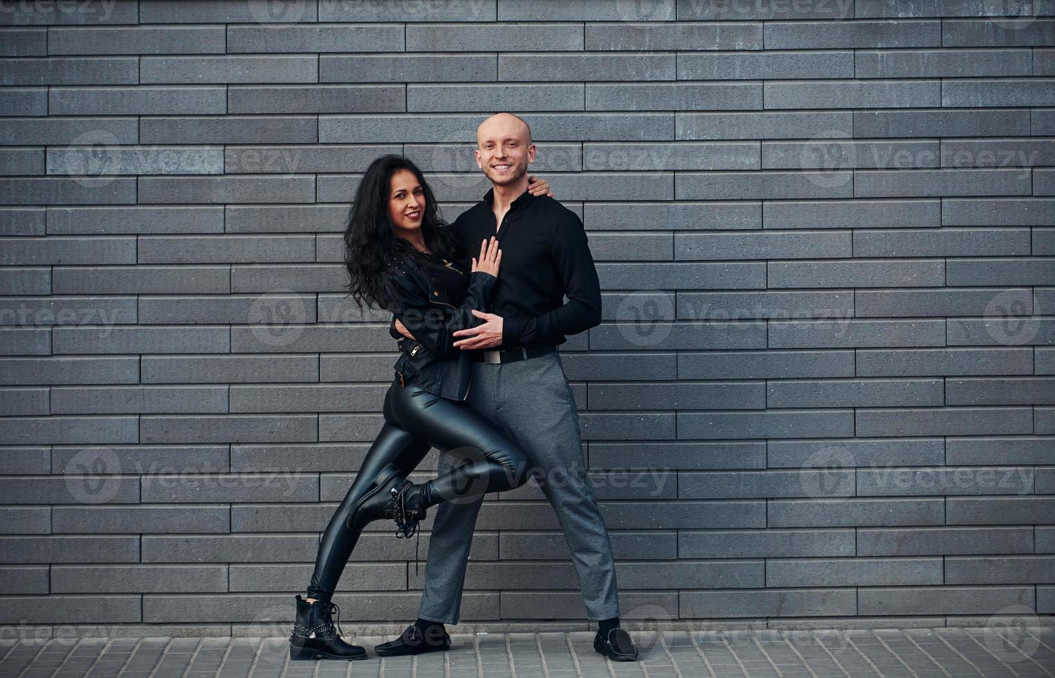 beau couple en vêtements noirs dansant ensemble contre le mur à l'extérieur photo