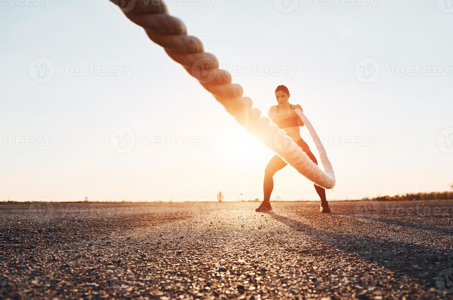 femme en tenue de sport s'entraînant avec des noeuds sur la route le soir photo