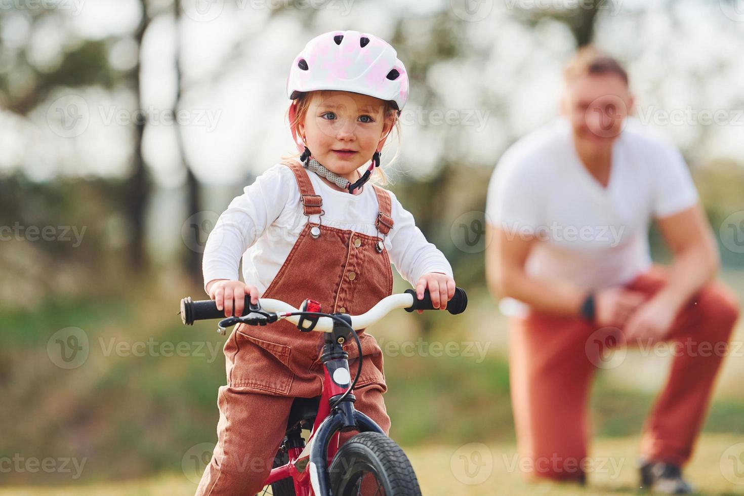 père en chemise blanche enseignant à sa fille comment faire du vélo à l'extérieur photo