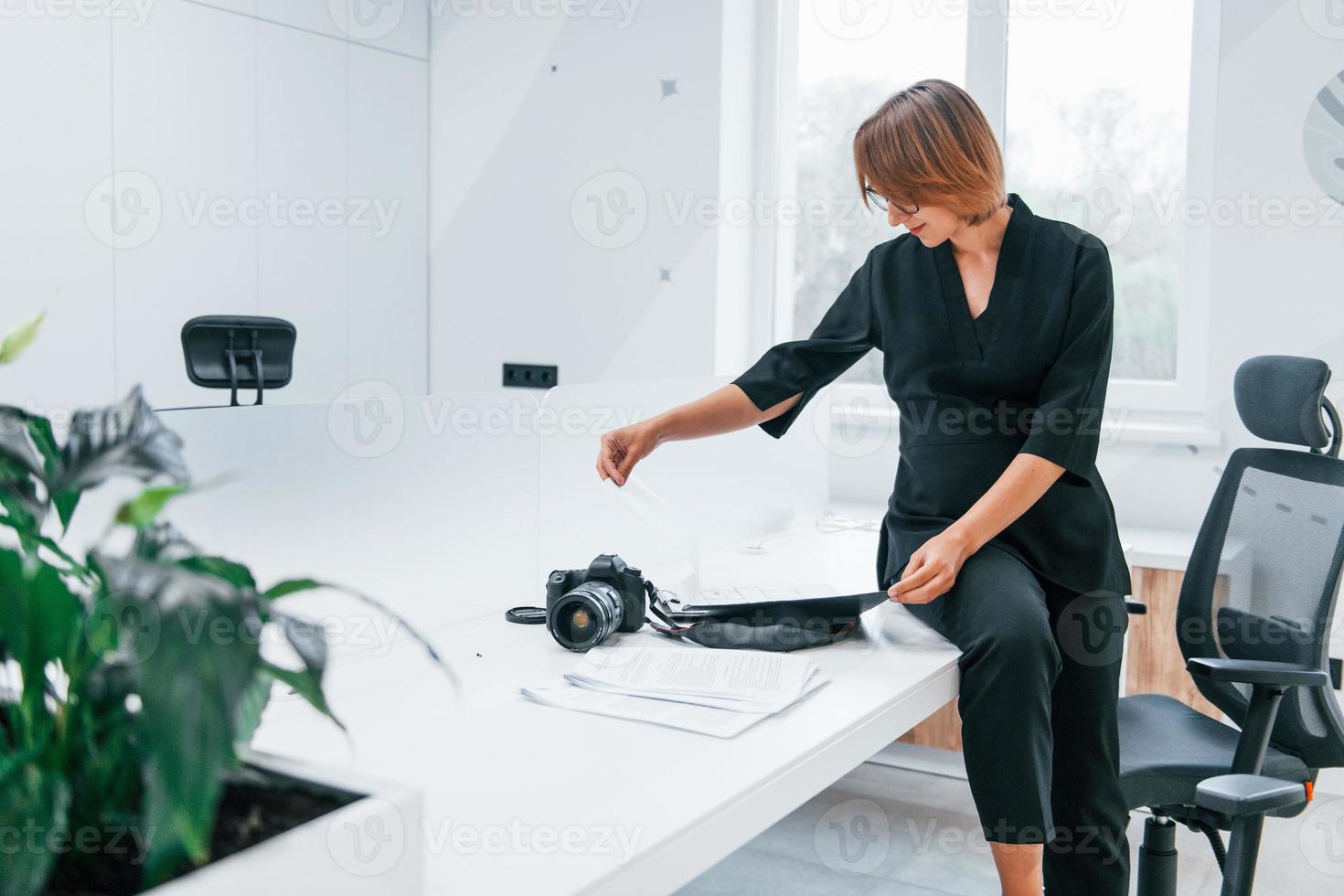 femme en vêtements formels noirs et avec caméra au bureau photo
