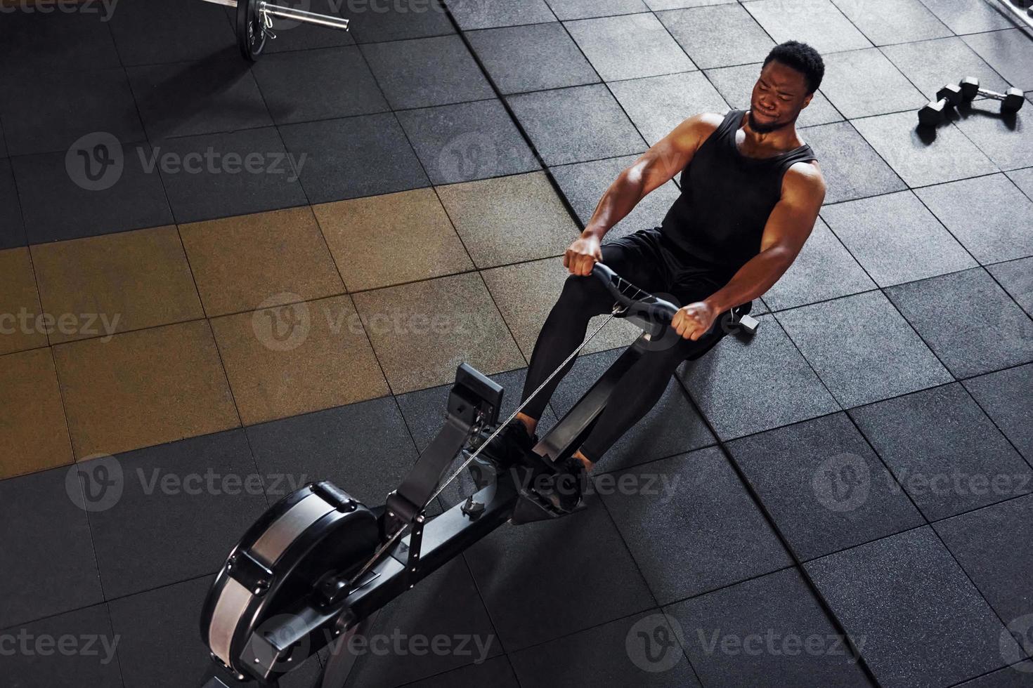 un homme afro-américain fort en vêtements sportifs a une journée d'entraînement dans la salle de sport et utilise de l'équipement. conception du pouvoir et de la force photo