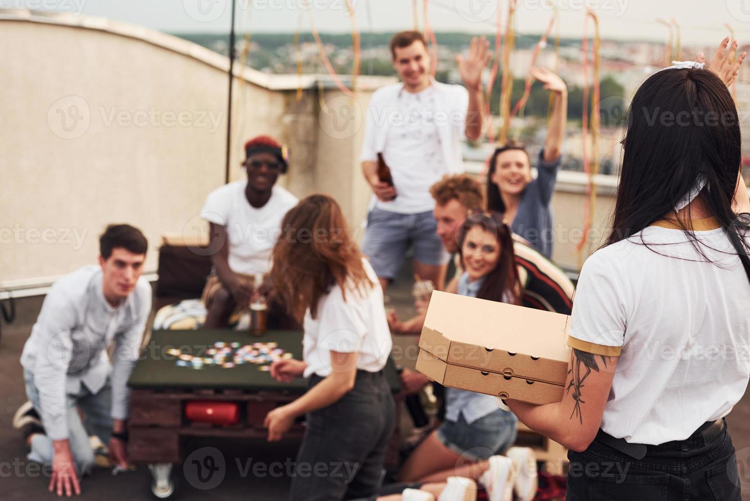 délicieuses pizzas. un groupe de jeunes en vêtements décontractés fait la fête ensemble sur le toit pendant la journée photo