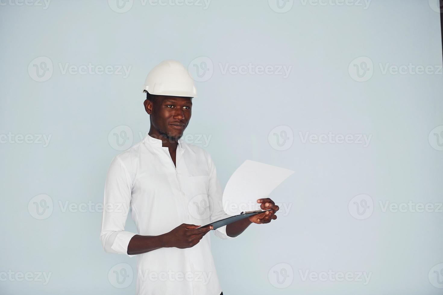 jeune ingénieur afro-américain en casque à l'intérieur avec bloc-notes dans les mains photo