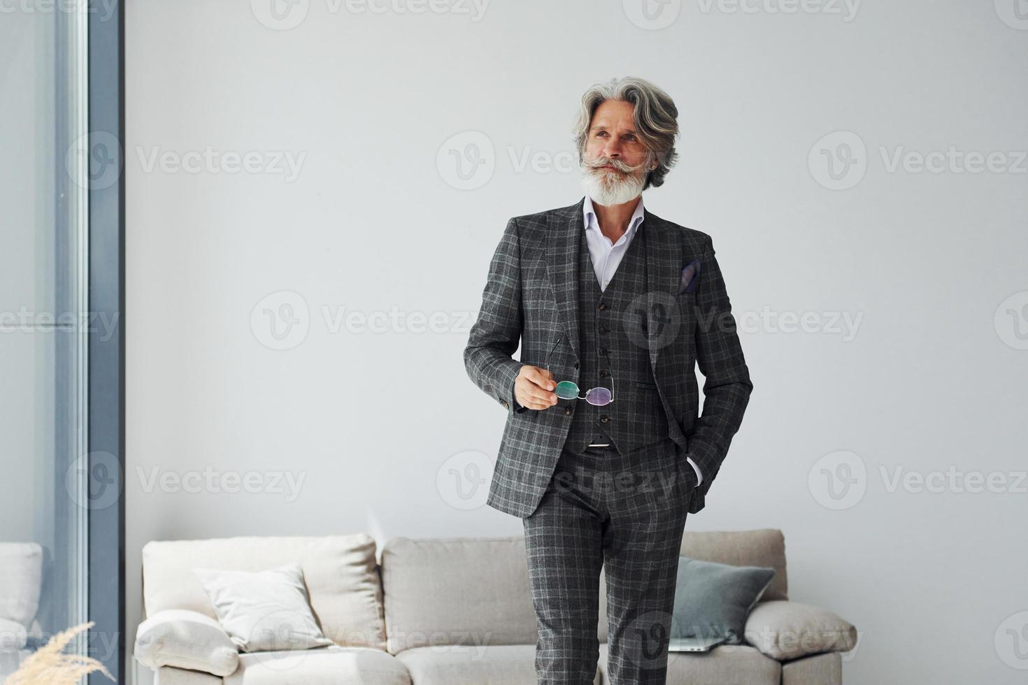 dans un appartement avec des vêtements élégants. homme moderne et élégant aux cheveux gris et à la barbe à l'intérieur photo