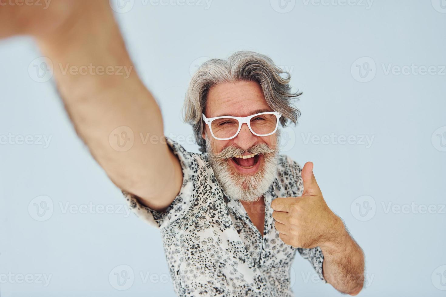 le touriste fait du selfie. homme moderne et élégant aux cheveux gris et à la barbe à l'intérieur photo