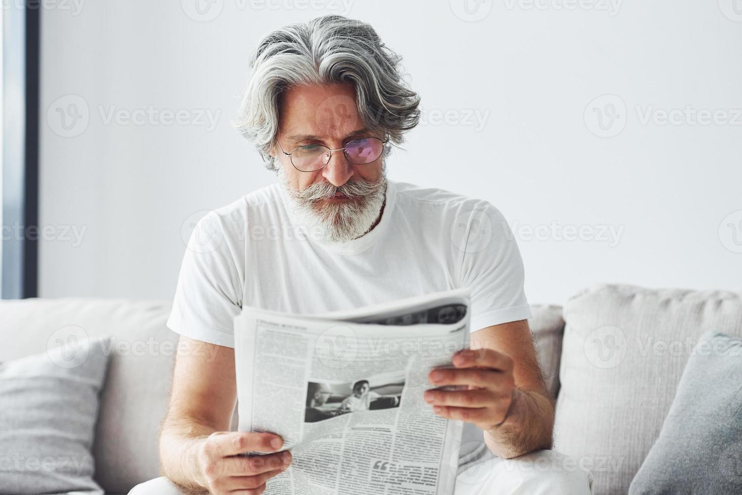 se reposer sur le canapé. homme moderne et élégant aux cheveux gris et à la barbe à l'intérieur photo