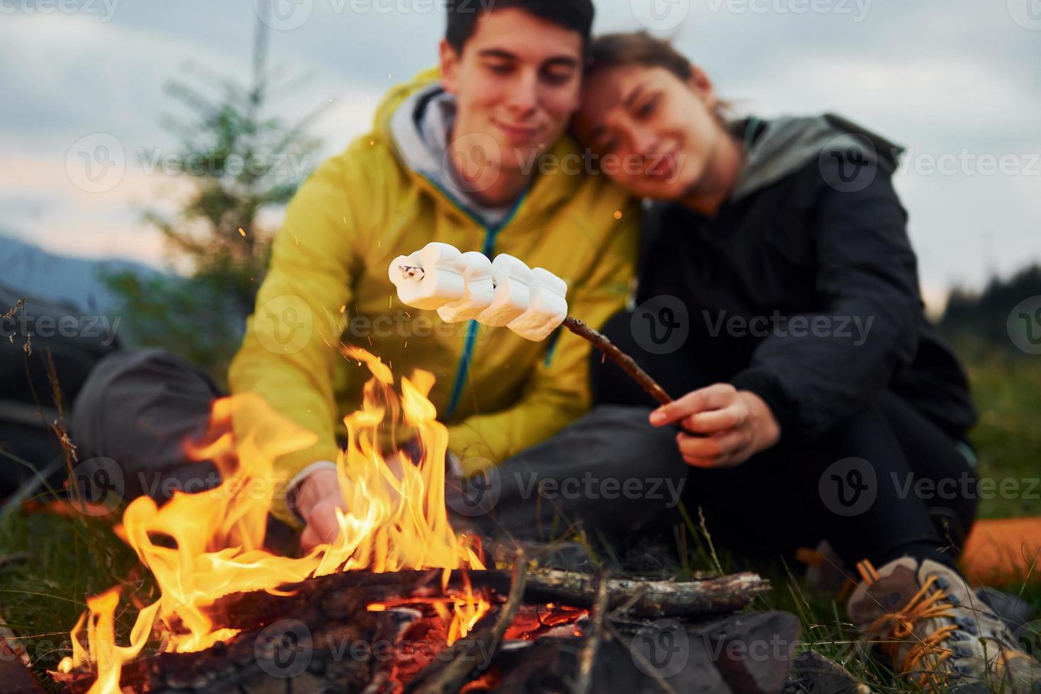 couple avec guimauve près du feu de camp. majestueuses montagnes des carpates. beau paysage de nature intacte photo