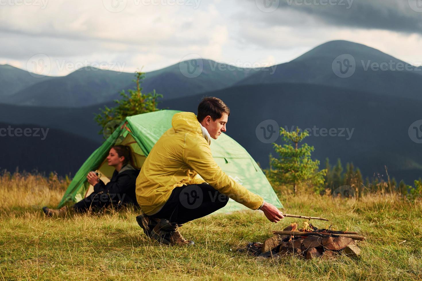 gars qui fait un feu de camp. petite amie vient de se réveiller. majestueuses montagnes des carpates. beau paysage de nature intacte photo