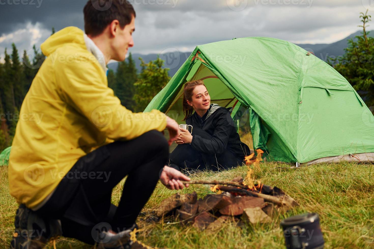 gars qui fait un feu de camp. petite amie vient de se réveiller. majestueuses montagnes des carpates. beau paysage de nature intacte photo