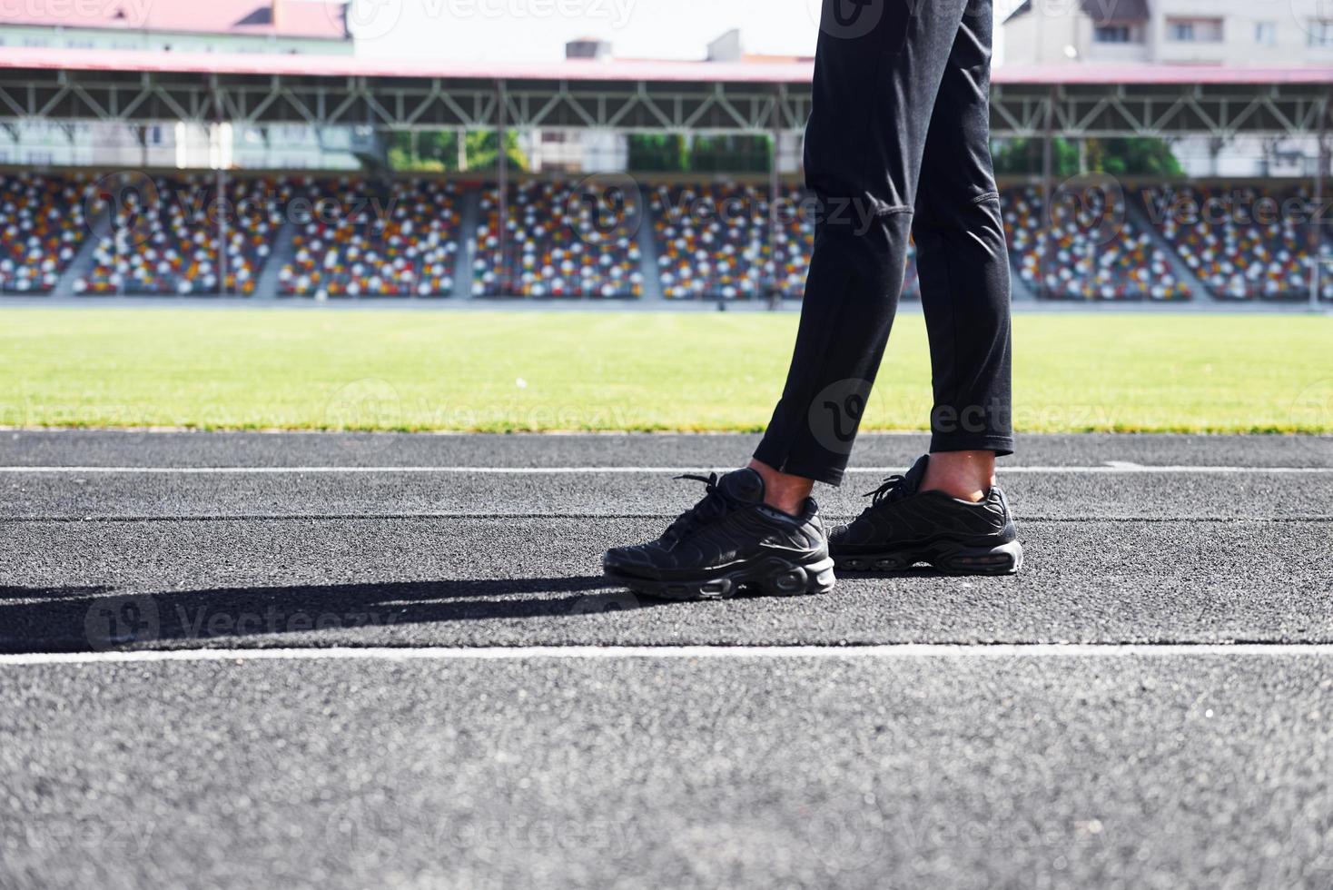 vue rapprochée des jambes du coureur en pantalon noir et chaussures qui est à l'extérieur sur la piste photo