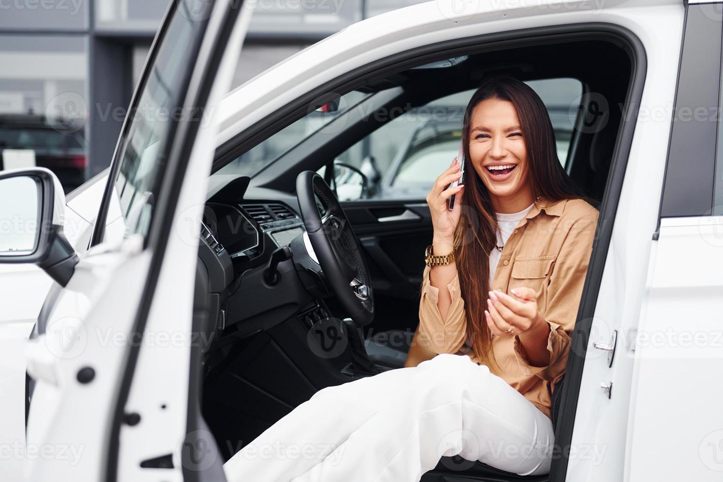 parle au téléphone avec la porte ouverte. belle jeune femme à la mode et son automobile moderne photo