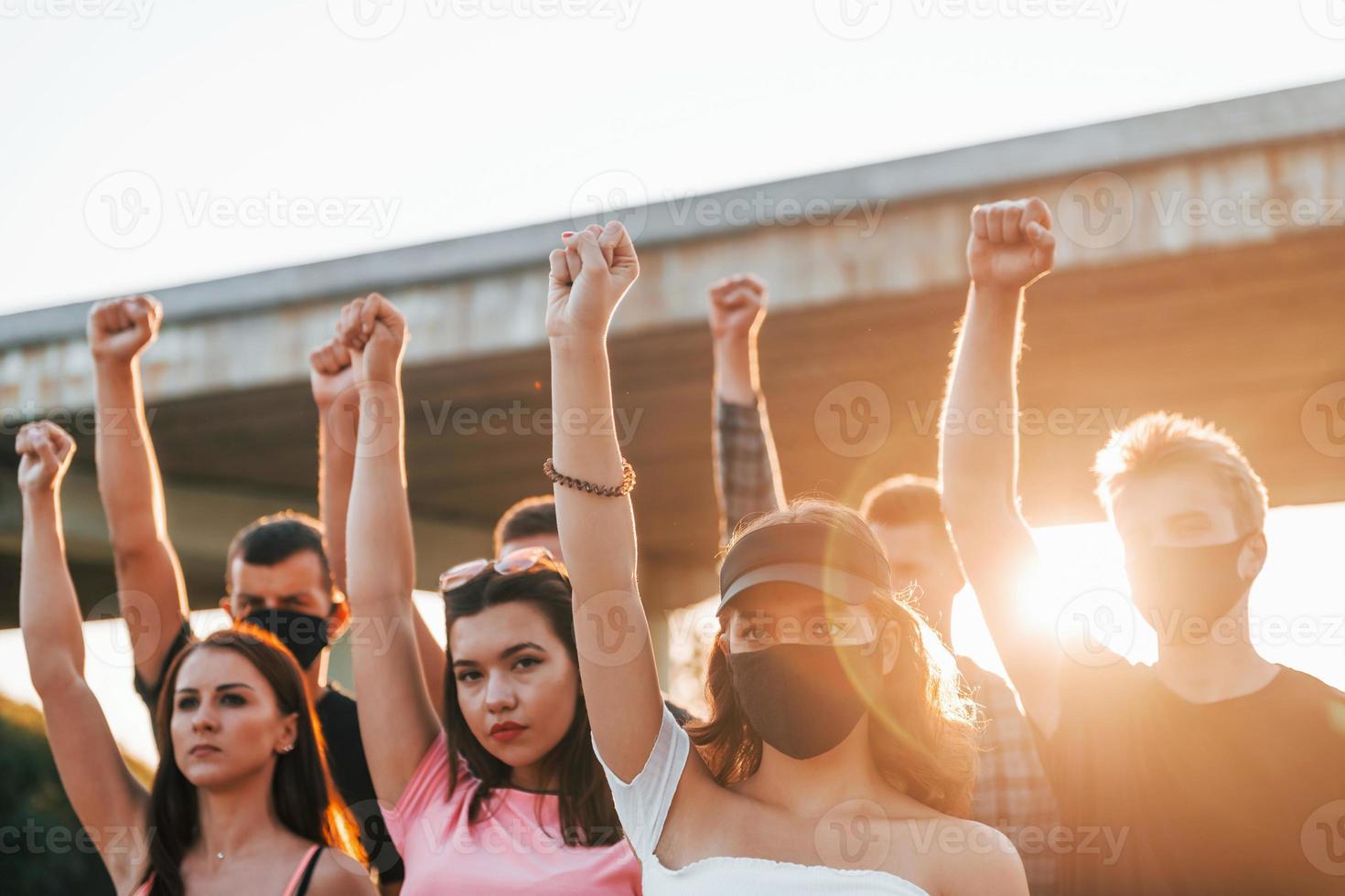 poings levés très haut. groupe de jeunes protestataires qui se tiennent ensemble. militant pour les droits de l'homme ou contre le gouvernement photo