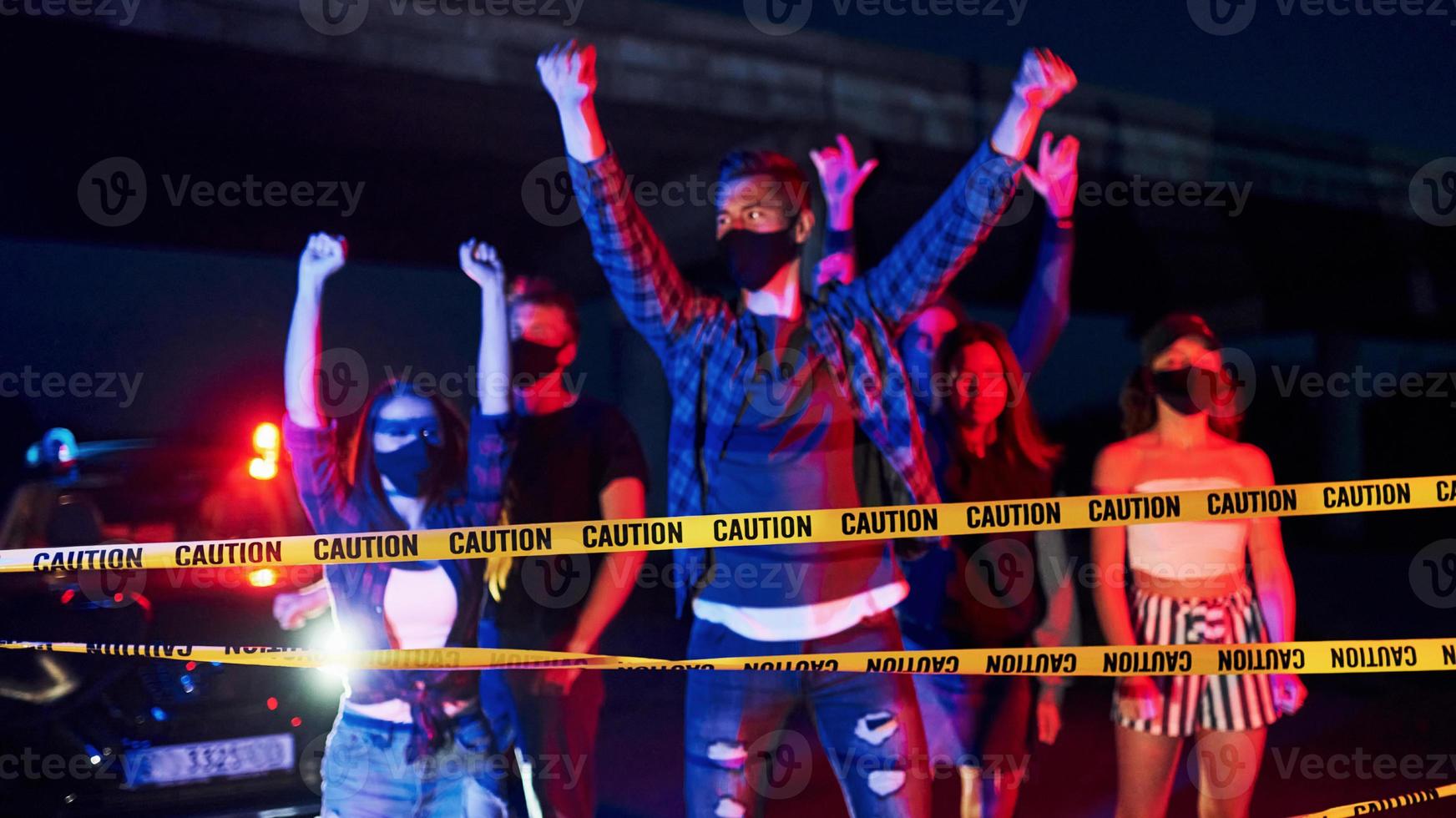 ruban de police de couleur jaune. groupe de jeunes protestataires qui se tiennent ensemble. militant pour les droits de l'homme ou contre le gouvernement photo