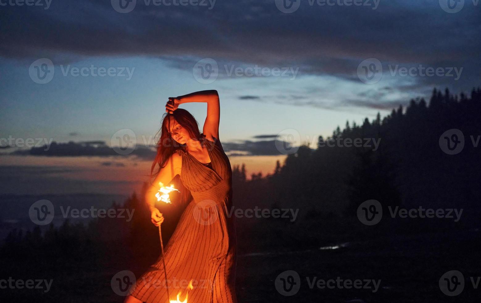 spectacle de feu par une femme en robe dans les montagnes des carpates de nuit. beau paysage photo