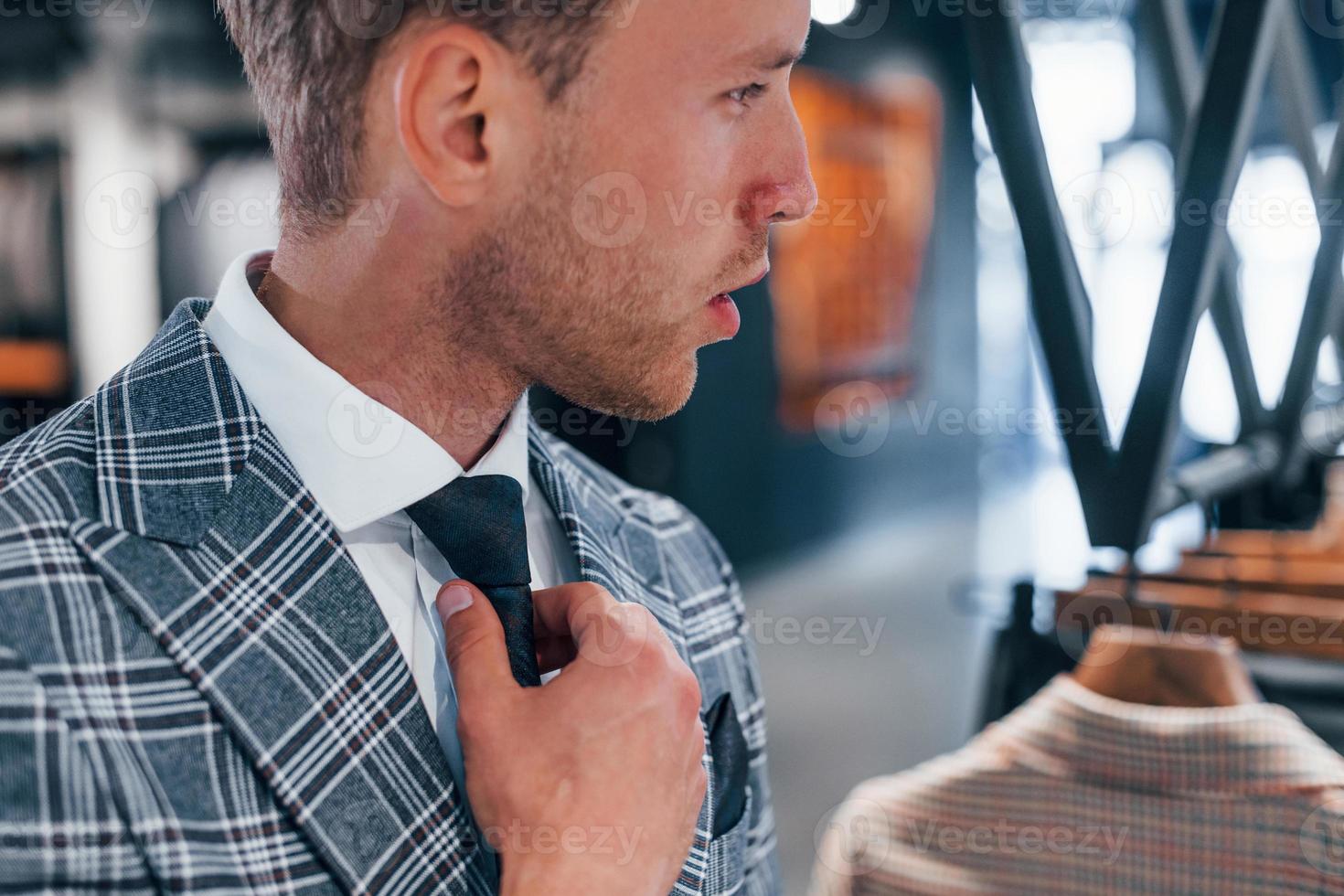 essaie de porter. jeune homme dans un magasin moderne avec de nouveaux vêtements. vêtements élégants et chers pour hommes photo