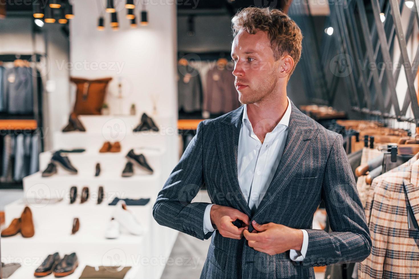 Jour de shopping. jeune homme dans un magasin moderne avec de nouveaux vêtements. vêtements élégants et chers pour hommes photo