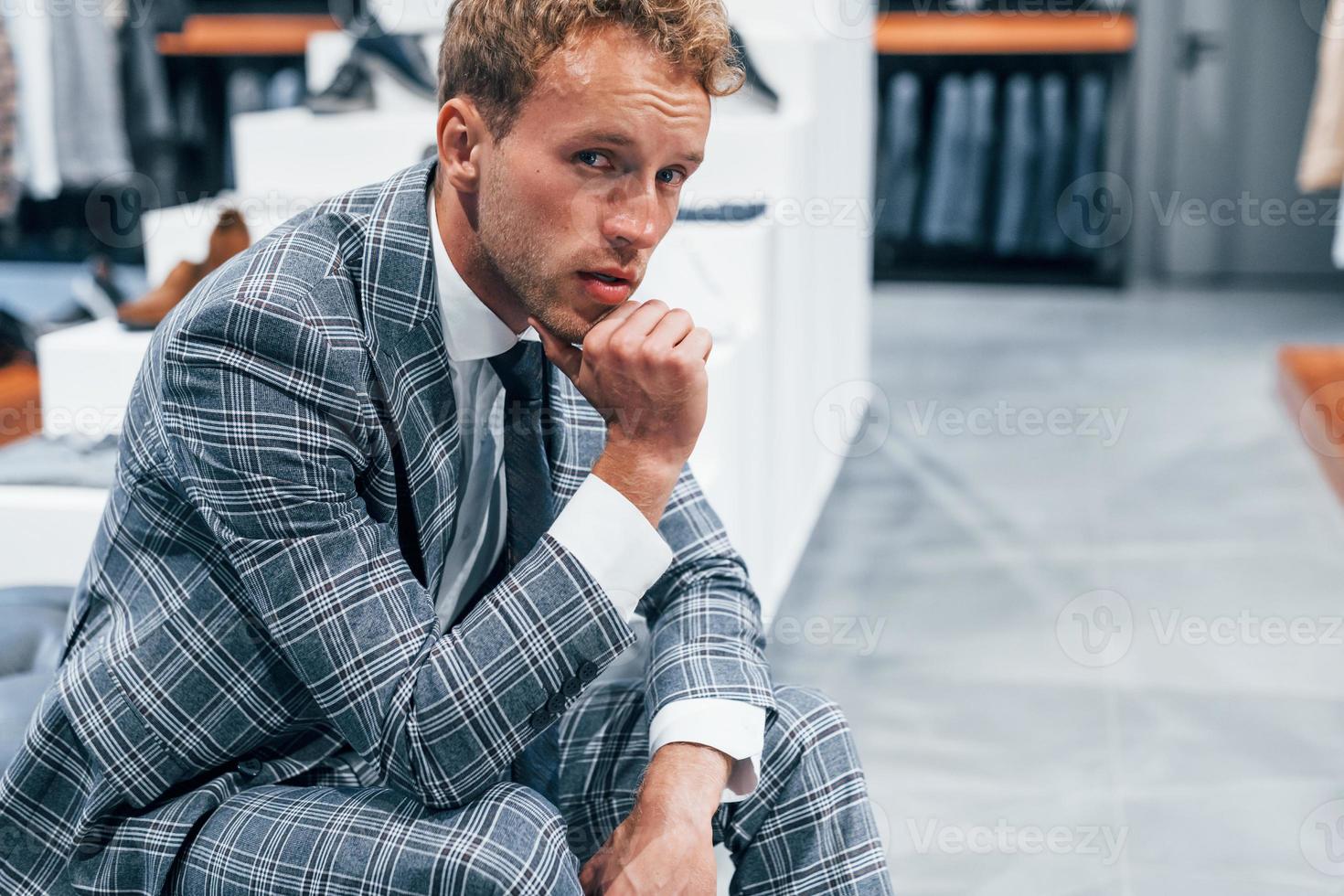 jeune homme dans un magasin moderne avec de nouveaux vêtements. vêtements élégants et chers pour hommes photo