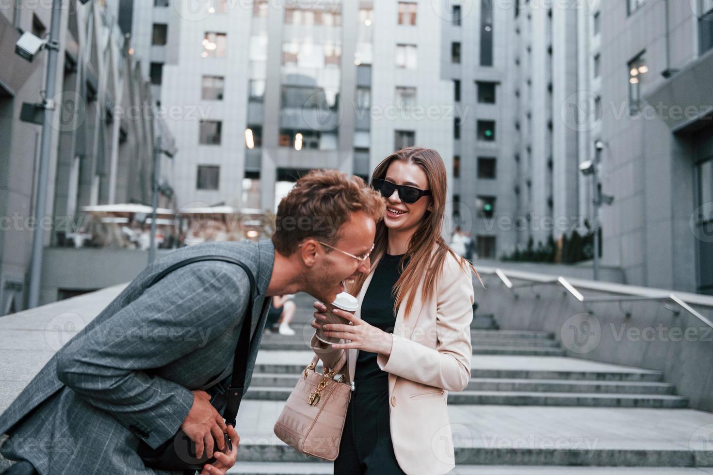 la fille tient la boisson. femme et homme dans la ville pendant la journée. des gens bien habillés photo