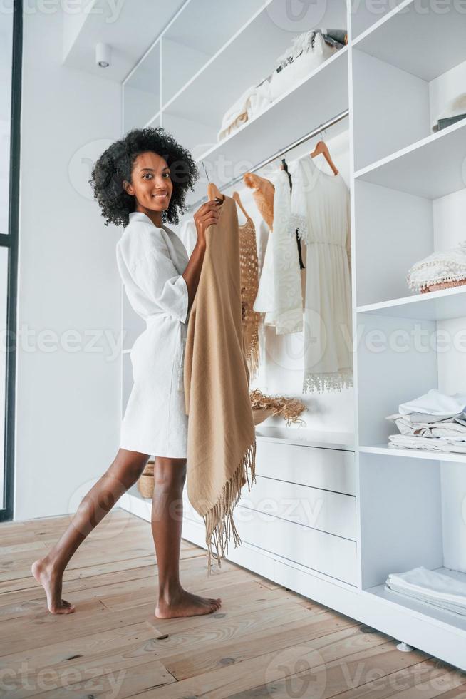 avec des vêtements différents. jeune femme afro-américaine aux cheveux bouclés à l'intérieur à la maison photo