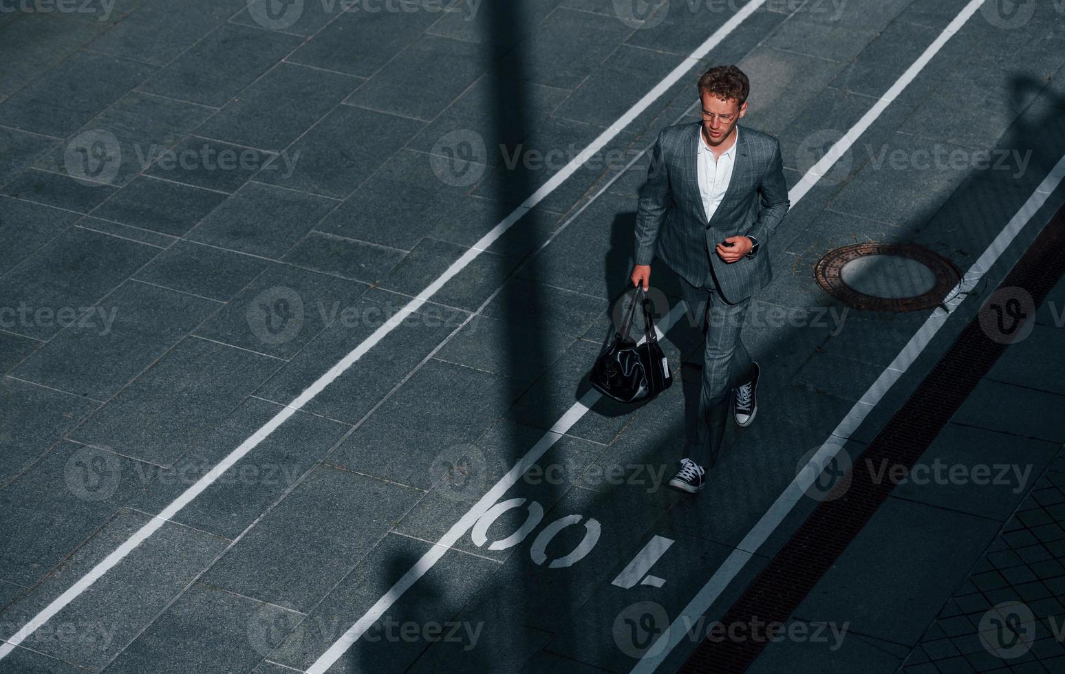 vue depuis le sommet. jeune homme d'affaires en tenue de soirée grise est à l'extérieur de la ville photo