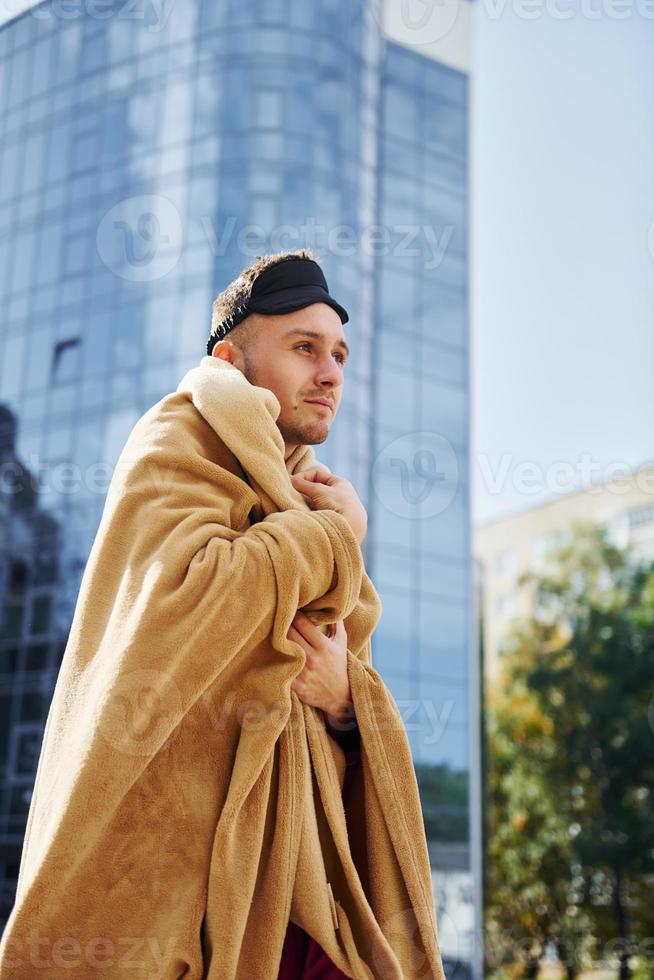 contre la création d'entreprise. jeune homme en pyjama est à l'extérieur dans la rue. se sent somnolent photo