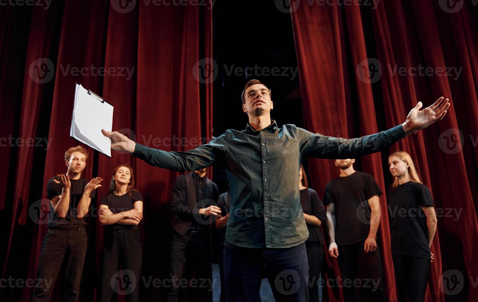 l'homme exerce son rôle. groupe d'acteurs vêtus de vêtements de couleur sombre en répétition au théâtre photo