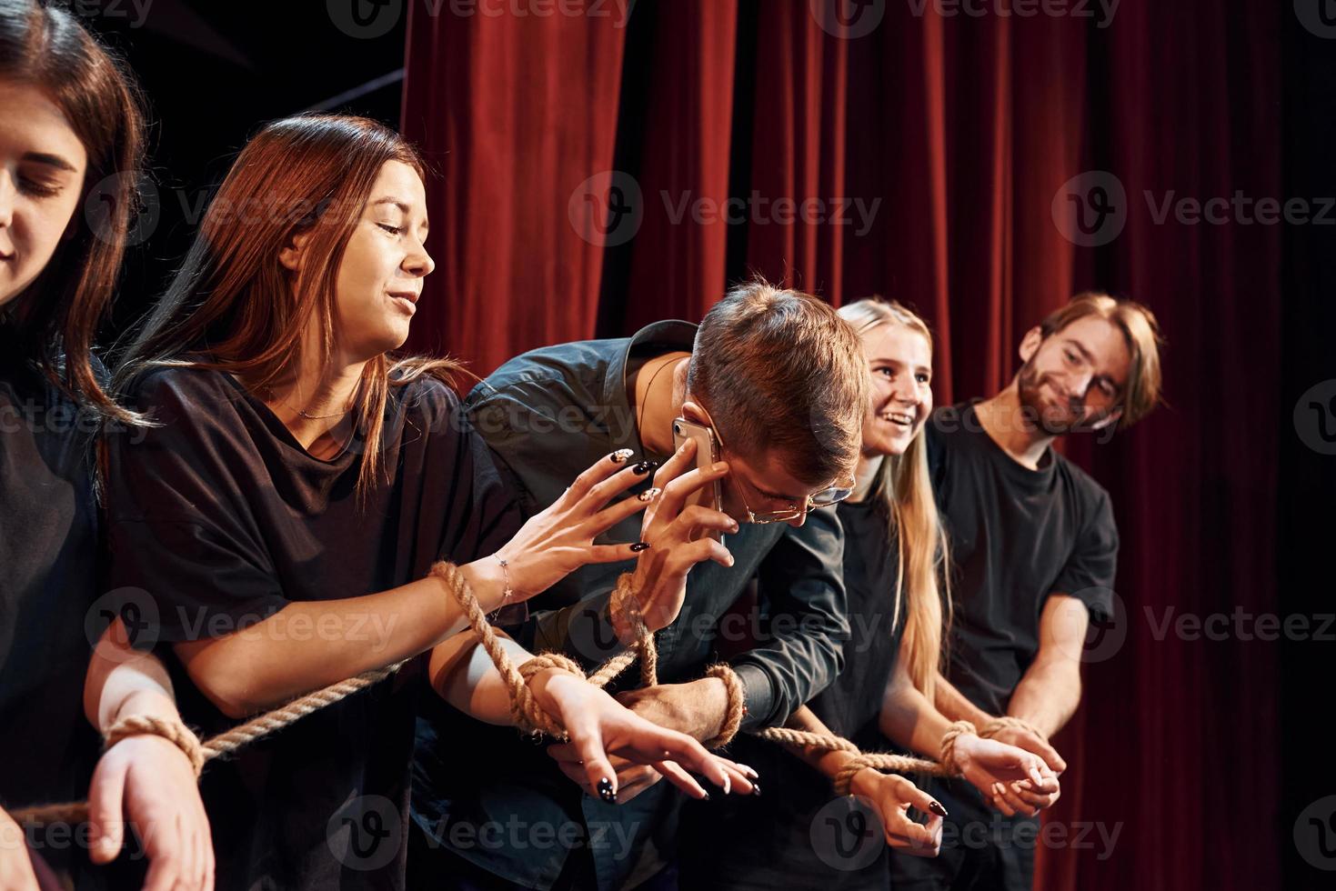 nœud dans les mains. groupe d'acteurs vêtus de vêtements de couleur sombre en répétition au théâtre photo