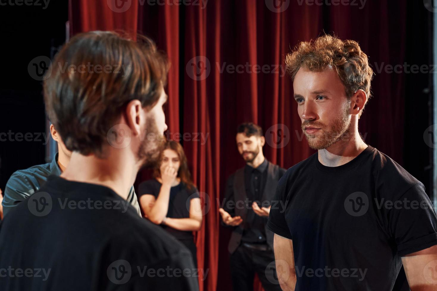 deux personnes qui parlent. groupe d'acteurs vêtus de vêtements de couleur sombre en répétition au théâtre photo